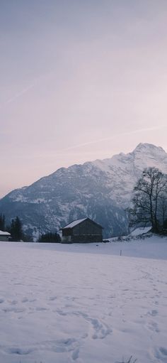 a snow covered field with mountains in the back ground and houses on the other side