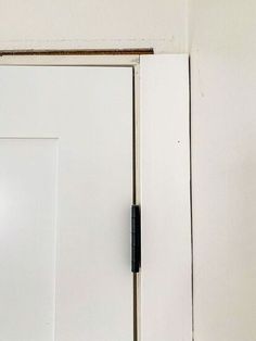 an open door with a black handle on the front and side doors in white painted walls