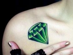 a woman's chest with a green diamond tattoo on her left shoulder and right arm