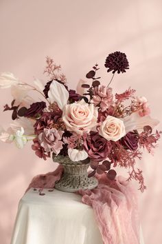 a vase filled with lots of flowers on top of a white tablecloth covered table