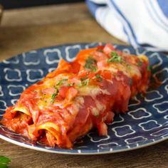 a blue plate topped with meat covered in sauce and garnish on top of a wooden table