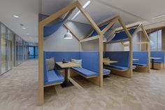 an empty room with blue booths and wooden tables in the center, along with glass walls