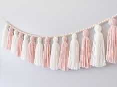 the tasselled garland is hanging on the wall with white and pink decorations around it