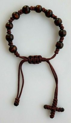 "Brown Wood & Cord Adjustable Rosary Bracelet with Woven Cross. THIS BRACELET IS TO BE USED BY MEN or WOMEN. ADJUSTS FROM 7\" - 9.5\" This listing is for (1) Bracelet. BEADS: Beads have are made of wood and are round in shape. They measure approx. 1/4\" in diameter. Beads are connected to the others with a cord. This is a very good quality and elegant rosary bracelet that you can wear anytime of the day. Please feel free to email me with questions about this item. Also please check my other Woven Cross, Rosary Bracelet, Made Of Wood, Brown Wood, Black Wood, Rosary, Classic Black, The Day, Beaded Necklace