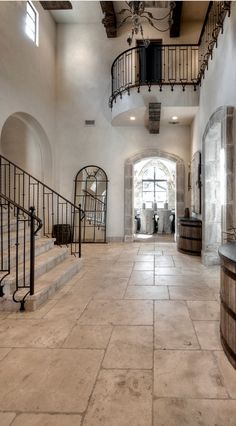 a large foyer with stone floors and wrought iron railings leading up to the second floor