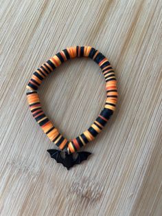 an orange and black bracelet with a bat on it