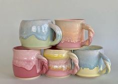 five different colored coffee mugs stacked on top of each other