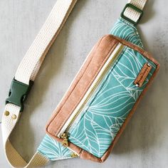 a blue and white purse sitting on top of a gray table next to a green strap