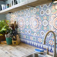 the kitchen counter is covered with colorful tiles and utensils, along with plants