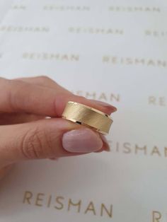 a woman's hand holding a gold ring on top of a piece of paper