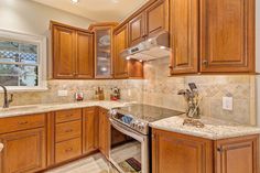 a kitchen with wooden cabinets and marble counter tops