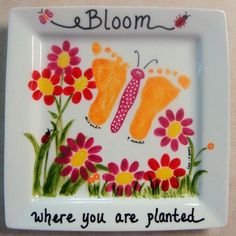 a white plate with flowers and butterflies painted on it that says bloom where you are planted