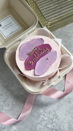 a birthday cake with pink frosting in a container