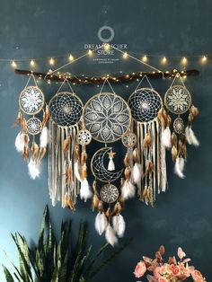 a wall hanging with several dream catchers and lights on top of it, next to a potted plant