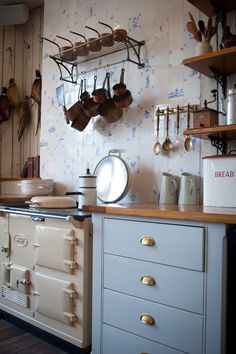 an old fashioned kitchen with pots and pans hanging on the wall above the stove