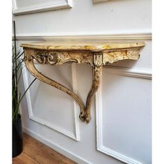 an ornate wooden shelf on the wall next to a potted plant