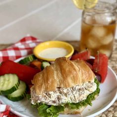 a sandwich with lettuce, tomatoes and cucumbers on a plate next to a drink