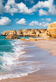 the beach has waves coming in and out of the water, with cliffs on either side