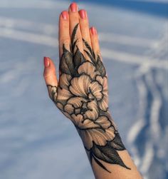 a woman's hand with a flower tattoo on her arm and the sky in the background