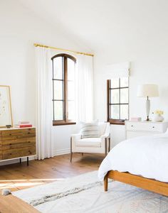 a bed room with a neatly made bed and two windows