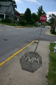 a stop sign on the corner of a street with graffiti painted on it's sidewalk