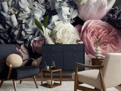 a living room with flowers on the wall and two chairs in front of it,