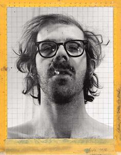 a man with long hair and glasses making a funny face in front of a grid background