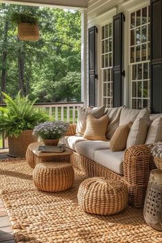 a porch with wicker furniture and potted plants on the front porch, surrounded by large windows