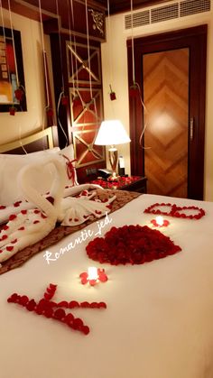 the bed is decorated with red rose petals and white linens, which have been cut into hearts