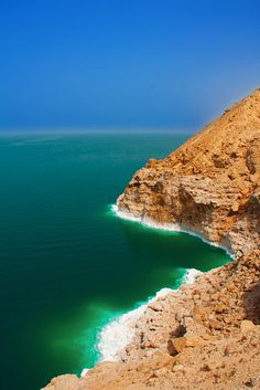 the water is very green and blue in this desert area with cliffs on either side