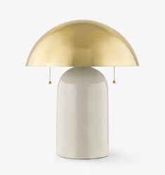 a white table lamp with a gold dome shade on it's top and base