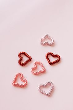 five heart shaped beads on a pink background