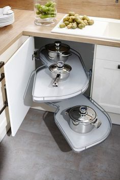 two pots and pans sit in the corner of a kitchen cabinet with drawers on both sides