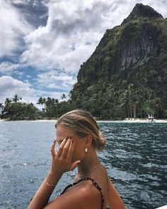 a woman is sitting on a boat looking at the water and mountains in the distance