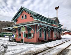 an old train station with snow on the ground and tracks in front of it,