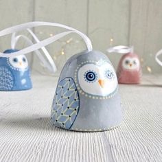 three ceramic owls sitting next to each other on top of a white table with lights in the background