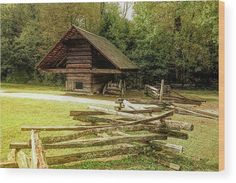 an old log cabin in the woods with a fence around it and trees behind it