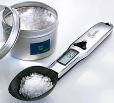 a digital scale and scoop full of sugar on a white table with the lid open