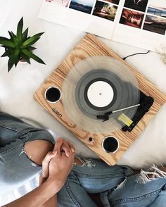 a record player sitting on top of a bed next to a potted plant and pictures