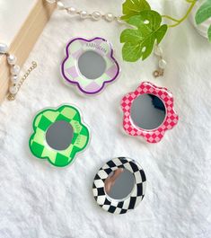 four different shaped mirrors sitting on top of a white table next to a green plant