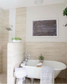 a white bath tub sitting next to a toilet under a framed sign on the wall