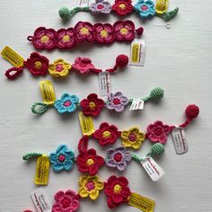 several crocheted flower clips are laid out on a white surface with tags attached to them