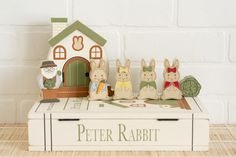 a group of wooden rabbits sitting in front of a small house on top of a book