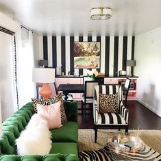 a living room with black and white stripes on the walls, green couches, zebra print rugs