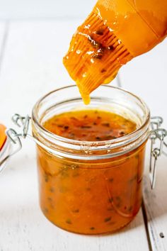 a jar filled with orange sauce being drizzled over it