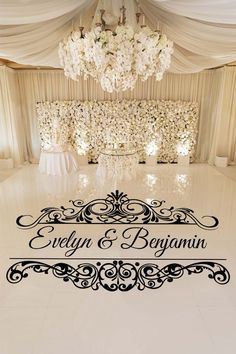 a white dance floor with black lettering on it and chandelier in the background