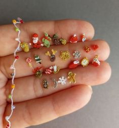 someone is holding their hand full of tiny christmas decorations and beadwork beads on it