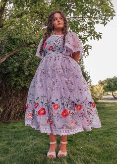 Lavender Haze And Summer Days This whimsical and enchanting piece captures the essence of springtime beauty. Its soft lavender hue is beautifully accented with vibrant floral embroidery, featuring bold red poppy blossoms, wildflowers, and delicate green vines. The puffed sleeves and flowing skirt add a playful and feminine touch, while the intricate lace trim along the hem enhances its charm. Perfect for a garden party or a dreamy outdoor event, this dress is designed to make you feel like you'r Purple Floral Applique Summer Dress, Summer Purple Dress With Floral Applique, Spring Embroidered Dress With Floral Applique And Short Sleeves, Spring Embroidered Dress With Floral Applique, Spring Floral Print Mauve Dress, Lavender Floral Applique Dress For Spring, Fitted Lavender Embroidered Dress, Spring Feminine Floral Embroidered Dress, Feminine Floral Embroidery Spring Dress