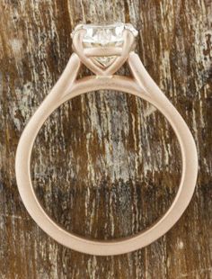 an engagement ring on top of a wooden table with a stone in the center and bottom