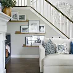 a white couch sitting under a stair case next to a fire place in a living room